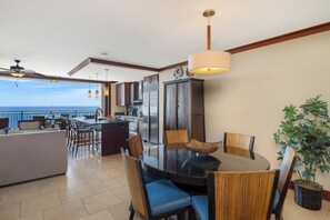 A modern kitchen with a dining area, large windows, and a view of the ocean.