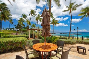 Relax in this serene outdoor seating area surrounded by lush greenery and ocean views.