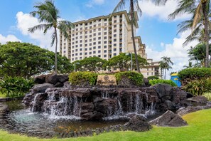 Ein Hotel mit Wasserfall, umgeben von üppiger Vegetation und Palmen.