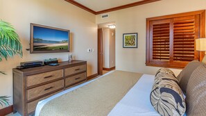 Ein Schlafzimmer mit Bett, Kommode, Fernseher und einem Fenster mit Jalousien.