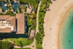 Vista aérea de un complejo turístico con piscina, playa y un edificio grande con techo de tejas.