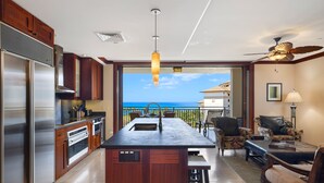 A modern kitchen with a central island, stainless steel appliances, and a view of the ocean.