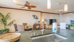 A modern kitchen with a granite countertop, stainless steel sink, and a ceiling fan.