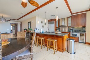 A spacious kitchen with a central island, wooden bar stools, a dining table with chairs, and modern appliances.