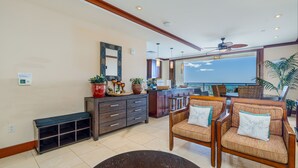A spacious living area with a large window, a ceiling fan, and a wooden bench.