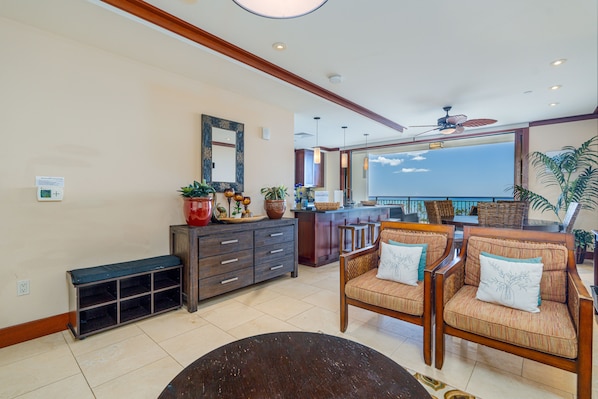 A spacious living area with a large window, a ceiling fan, and a wooden bench.
