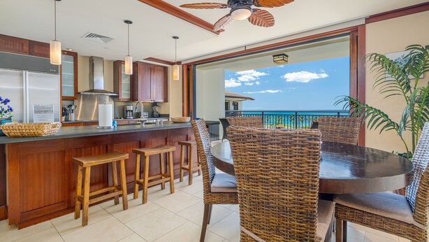 A modern kitchen with a bar area, wicker furniture, and a view of the ocean.