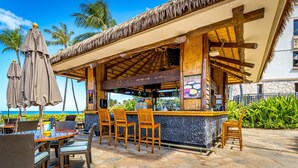 Un bar sulla spiaggia con mobili in legno e tetto di paglia.