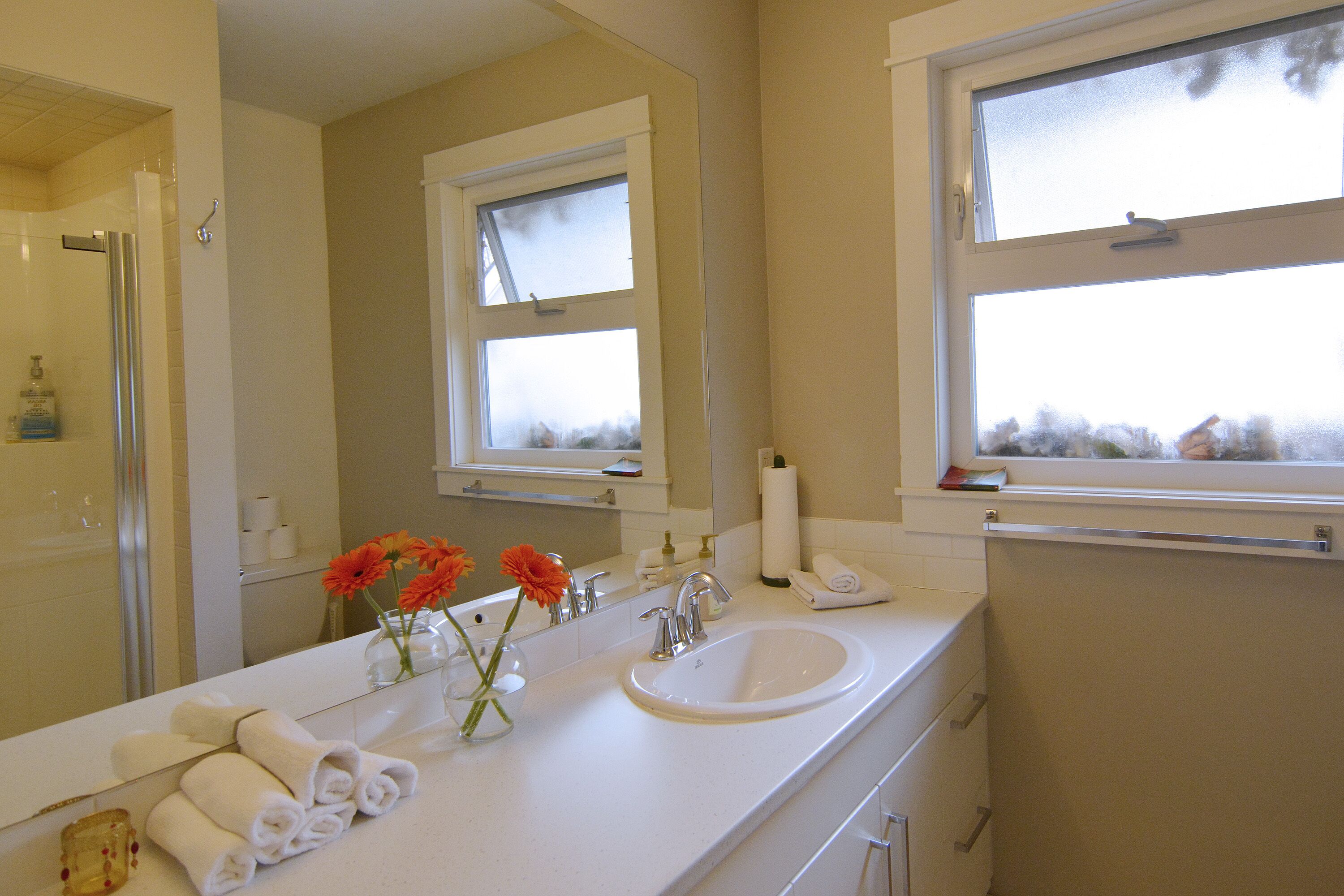 A bathroom with a large mirror, a sink, and a window.