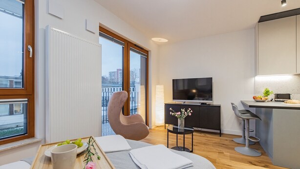Une chambre d’hôtel moderne dotée d’une grande fenêtre, d’un fauteuil confortable, d’un coin repas et d’une télévision.