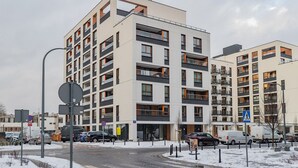 Un immeuble résidentiel à plusieurs étages, doté de balcons, d’un passage piéton et d’une zone de stationnement.