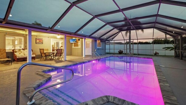 Una piscina interior amb sostre de vidre i zona de terrassa amb mobiliari d'exterior.