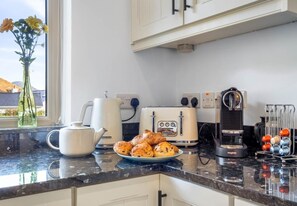 Eine Küche mit Kaffeemaschine, Toaster, Wasserkocher und einem Tablett Gebäck.