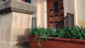 A building with a sign reading "Bella Vista" above a wooden door. There is a red planter with green plants and a red flower in front of the door. - Peaceful Haven With Stunning Views Close to sea (Marsaskala)