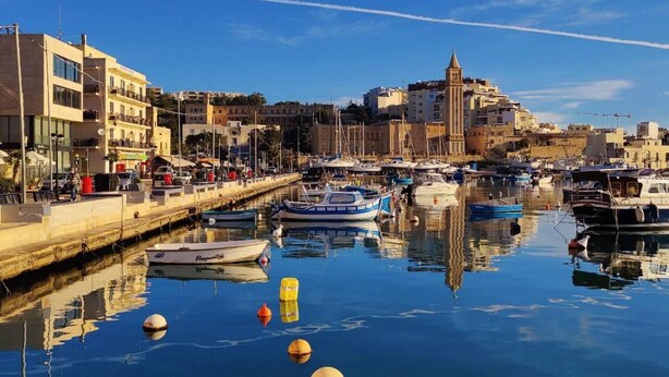 A harbor with boats docked, a waterfront promenade, and buildings in the background. - Peaceful Haven With Stunning Views Close to sea (Marsaskala)