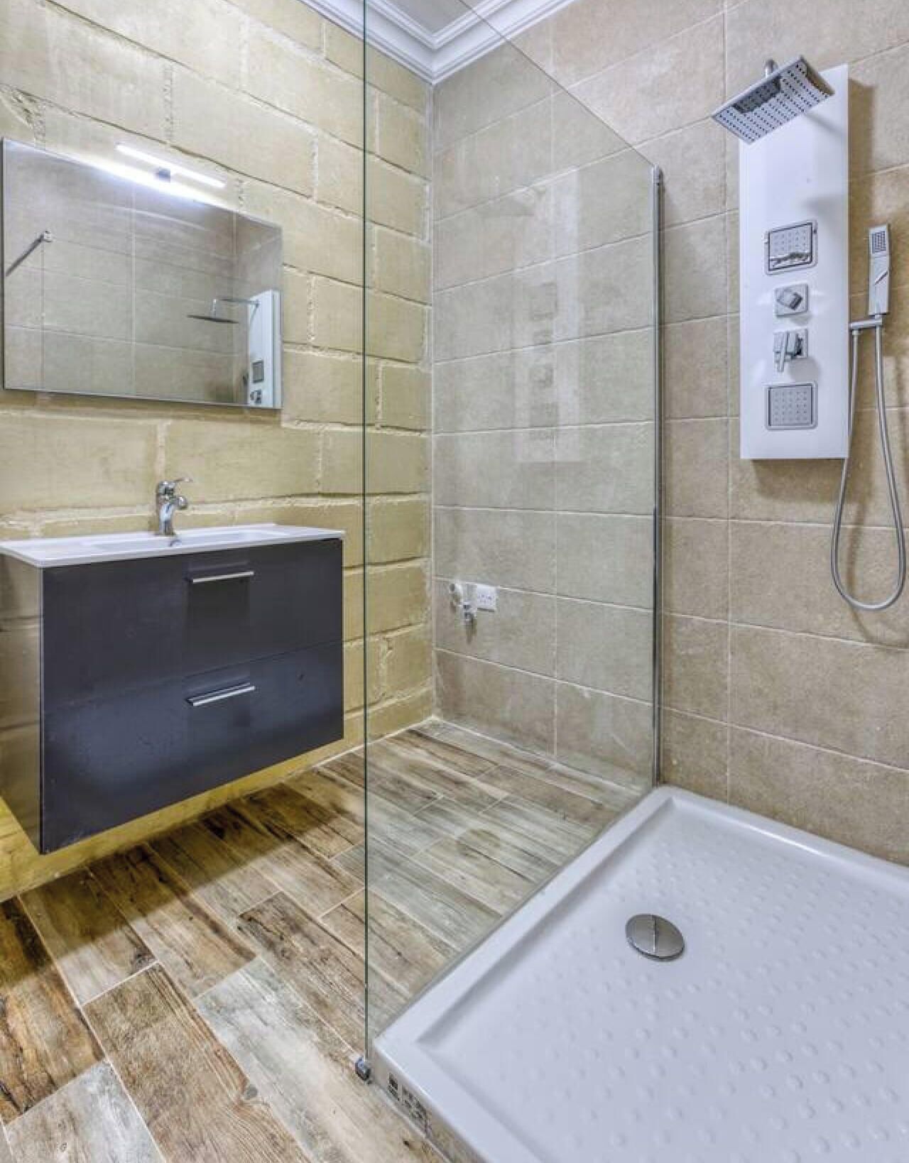 Un bagno moderno con doccia vetrocamera, mobile lavabo e specchio.