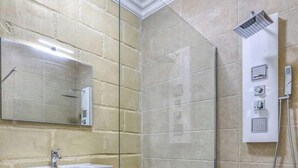 A modern bathroom with a glass-enclosed shower, a vanity with a sink, and a mirror.