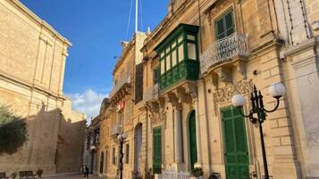 Un edificio storico con architettura classica, caratterizzato da persiane verdi e balconi decorati.