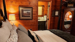 Een gezellig houten blokhut slaapkamer met een hemelbed, een houten hoofdbord en een grote spiegel.