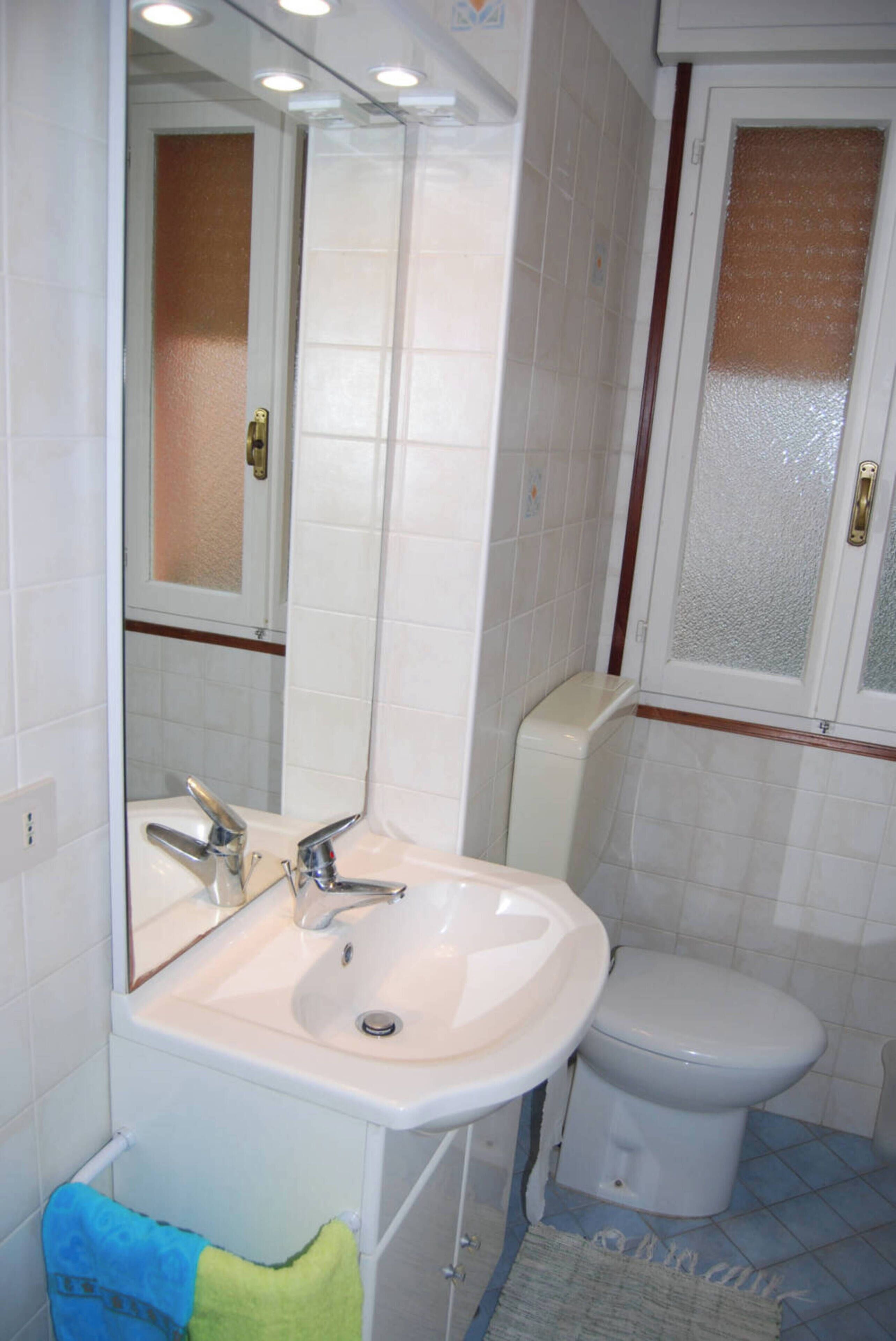 A bathroom with a white sink, a mirror, and a toilet.