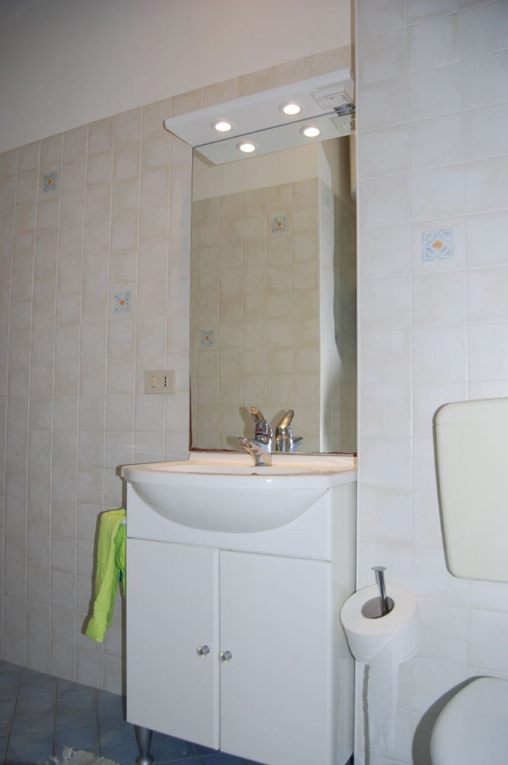 A bathroom with a white sink, mirror, and toilet.