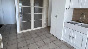 Moderni keittiö, jossa on valkoiset kaapit, integroitu pesuallas ja suuri ikkuna.
