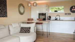 A modern kitchen with white cabinets, a central island, and pendant lighting. - Core-na-bye (Inverness)