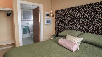 Un dormitorio con una cama verde, cabecera con estampado de jirafa y una lámpara colgante.