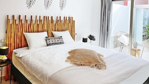 A bed with a wooden headboard, white bedding, and a decorative throw.