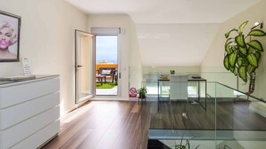Una sala de estar moderna con una escalera de cristal, un comedor con asientos exteriores y vistas al cielo.