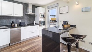 Una cocina moderna con armarios blancos, lavavajillas, microondas y cafetera.