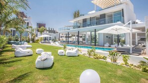 Un resort moderno con piscina, mobiliario exterior y un edificio grande con balcones.