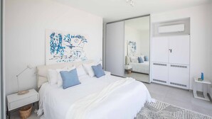 Un dormitorio moderno con una cama grande, paredes blancas y un armario.