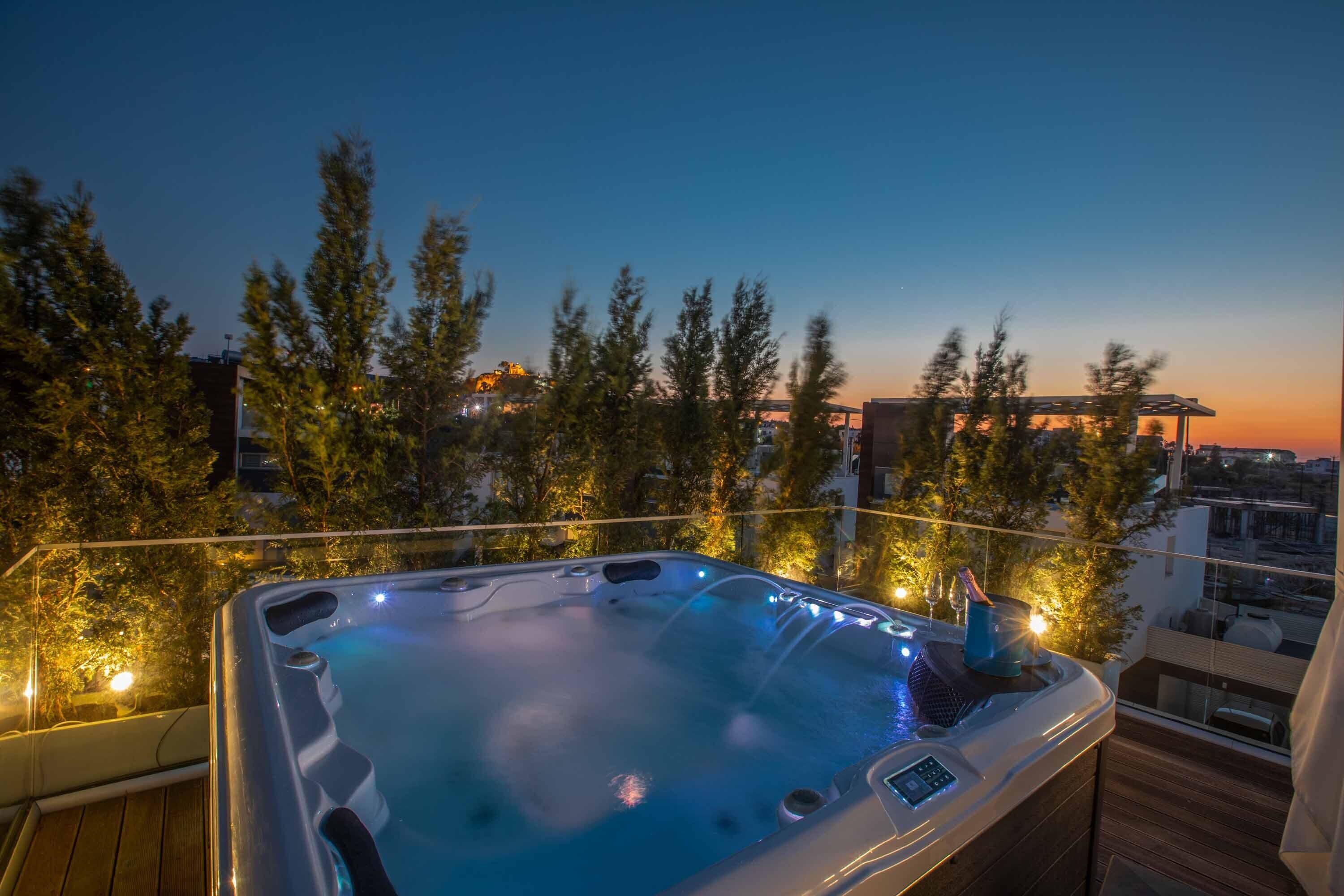 Un jacuzzi en un balcón con vista a la ciudad al anochecer.