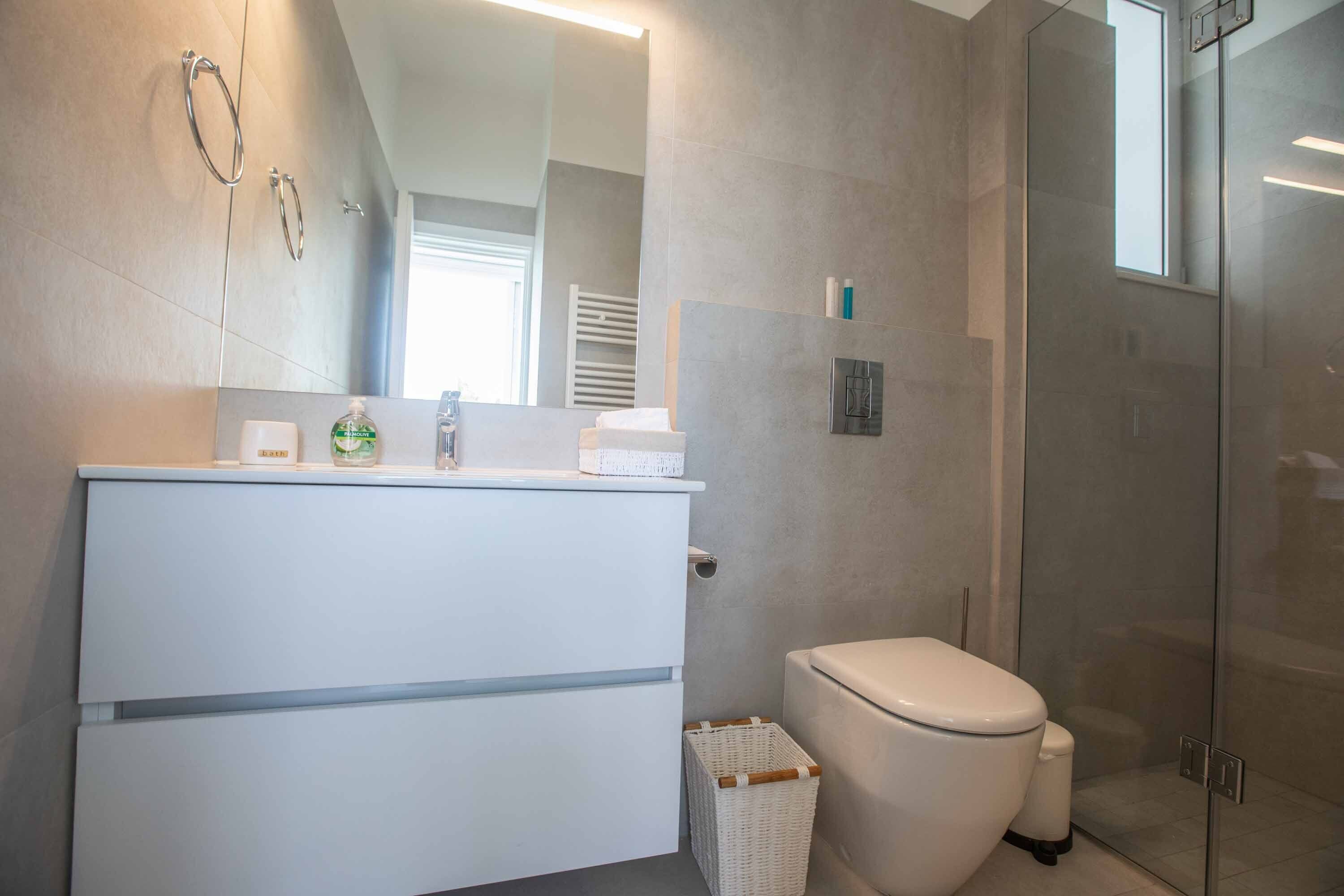 Un baño moderno con tocador blanco, inodoro y cabina de ducha de vidrio.