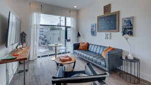 A modern living room with a grey sofa, a wooden coffee table, a TV, and artwork on the walls.