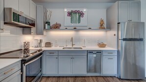 A modern kitchen with white cabinets, stainless steel appliances, and a central island.