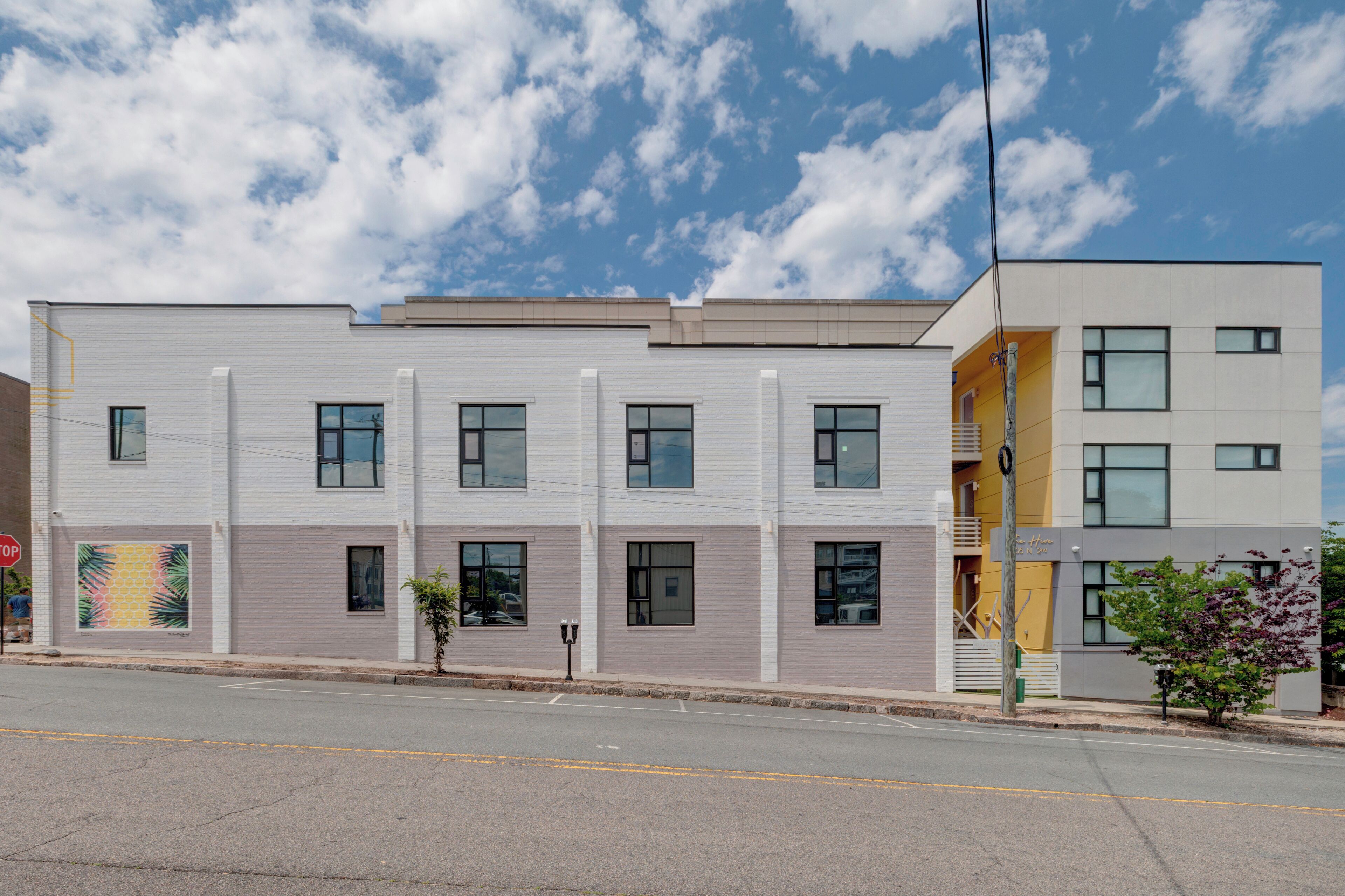 A modern two-story building with a flat roof, large windows, and a visible entrance.