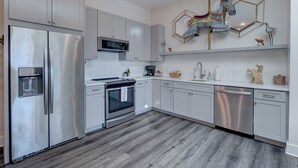 A modern kitchen with stainless steel appliances, white cabinets, and a wooden floor. - The Hive 205 Sweeter (Wilmington)