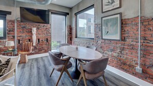 A modern meeting room with a brick wall, large windows, and a round table with chairs. - The Hive 207 Bees Knees by BlueStar (Wilmington)
