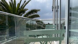 A balcony with a green chair and a glass railing. - Immaculate Studio Apartment Just Outside Penzance (Penzance)