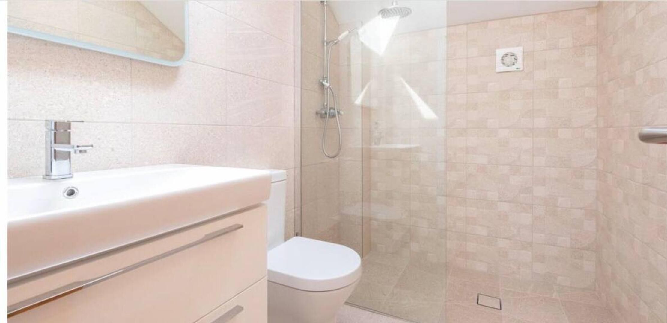 Un baño con lavamanos blanco, inodoro y cabina de ducha de vidrio.