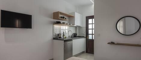 Una cocina moderna con lavavajillas integrado, un televisor de pantalla plana y un estante de madera sobre la encimera.