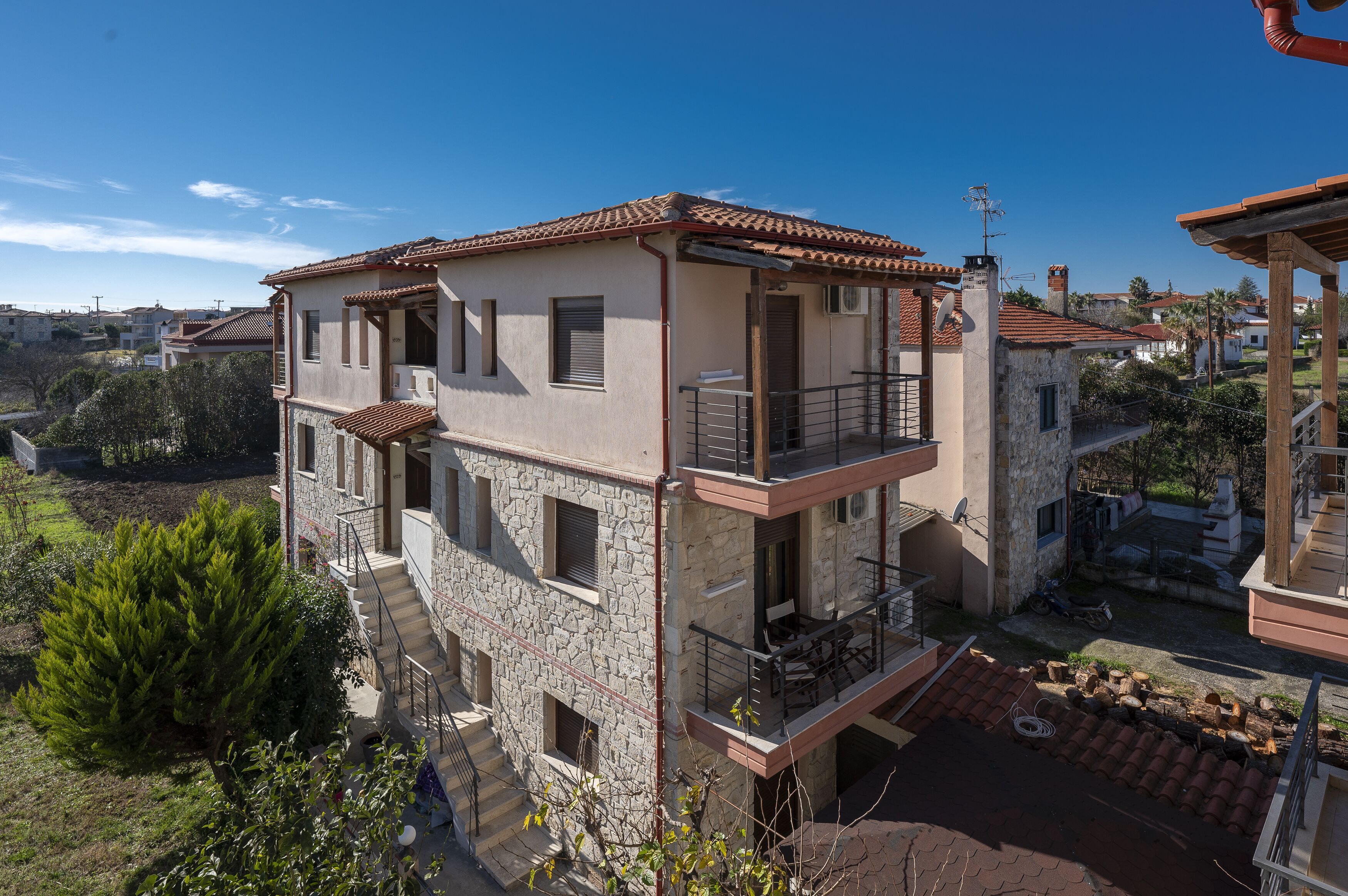 Un edificio de varios pisos con balcones, fachada de piedra y vista despejada del barrio circundante.