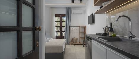 A modern bedroom with a large bed, a small desk, and a window with curtains.
