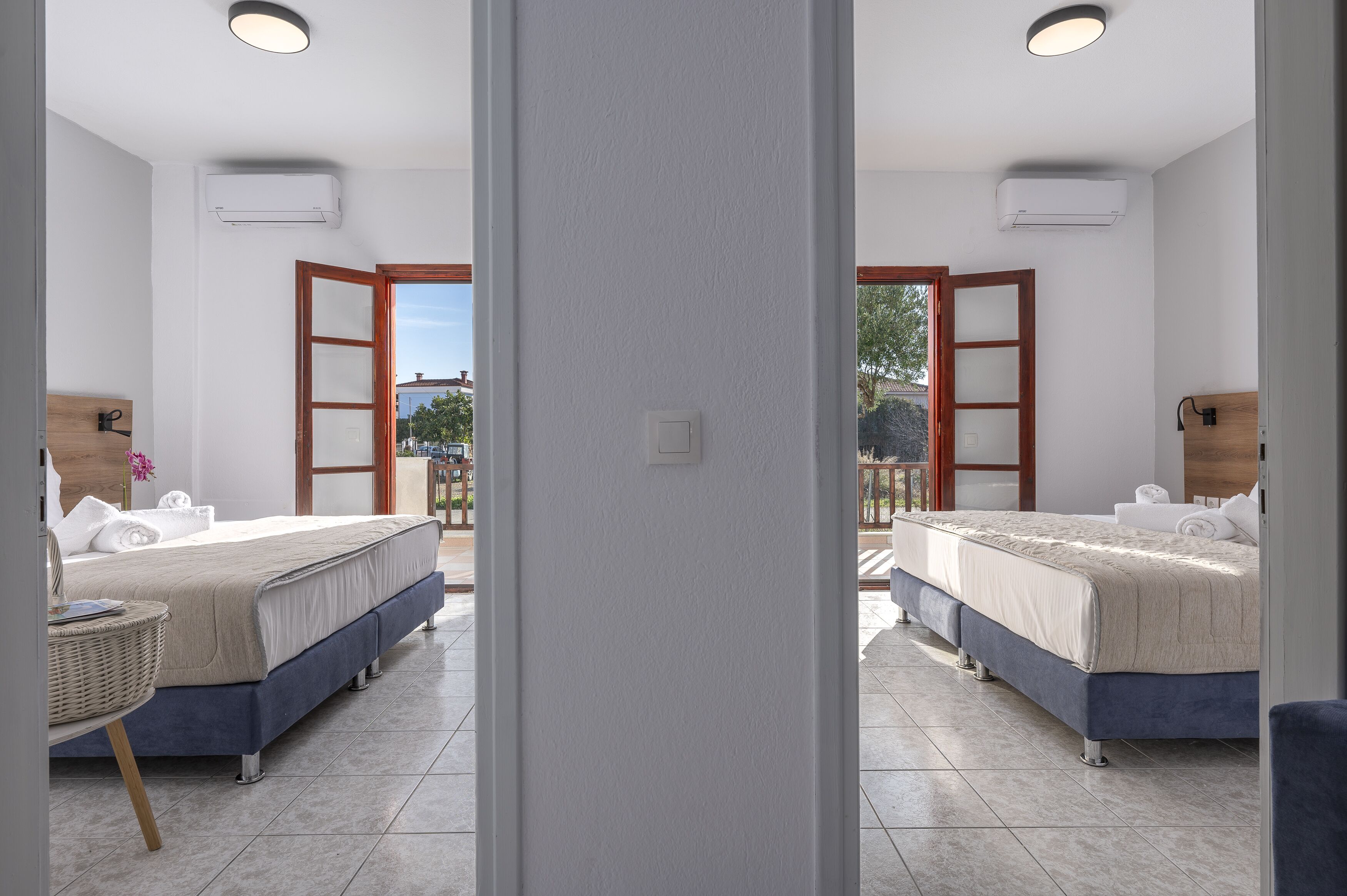 A hotel room with two beds, a balcony, and a view of the outside.