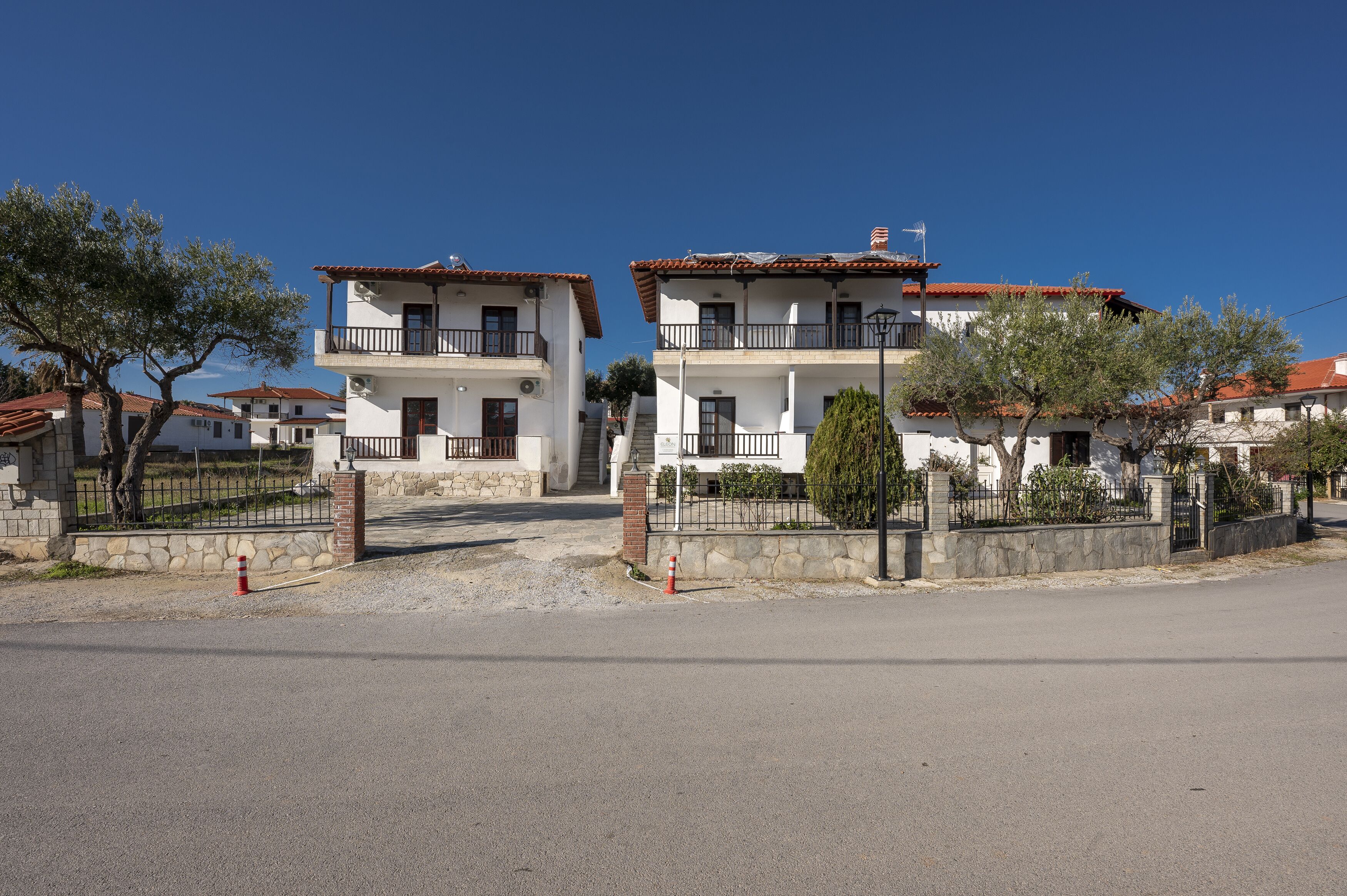 A residential building with a two-story structure, a balcony on the upper floor, and a red-tiled roof.