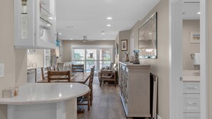 A spacious kitchen with white cabinetry, a central island, and a dining area with wooden chairs. - Pet Friendly with Gulf Views! (Miramar Beach)