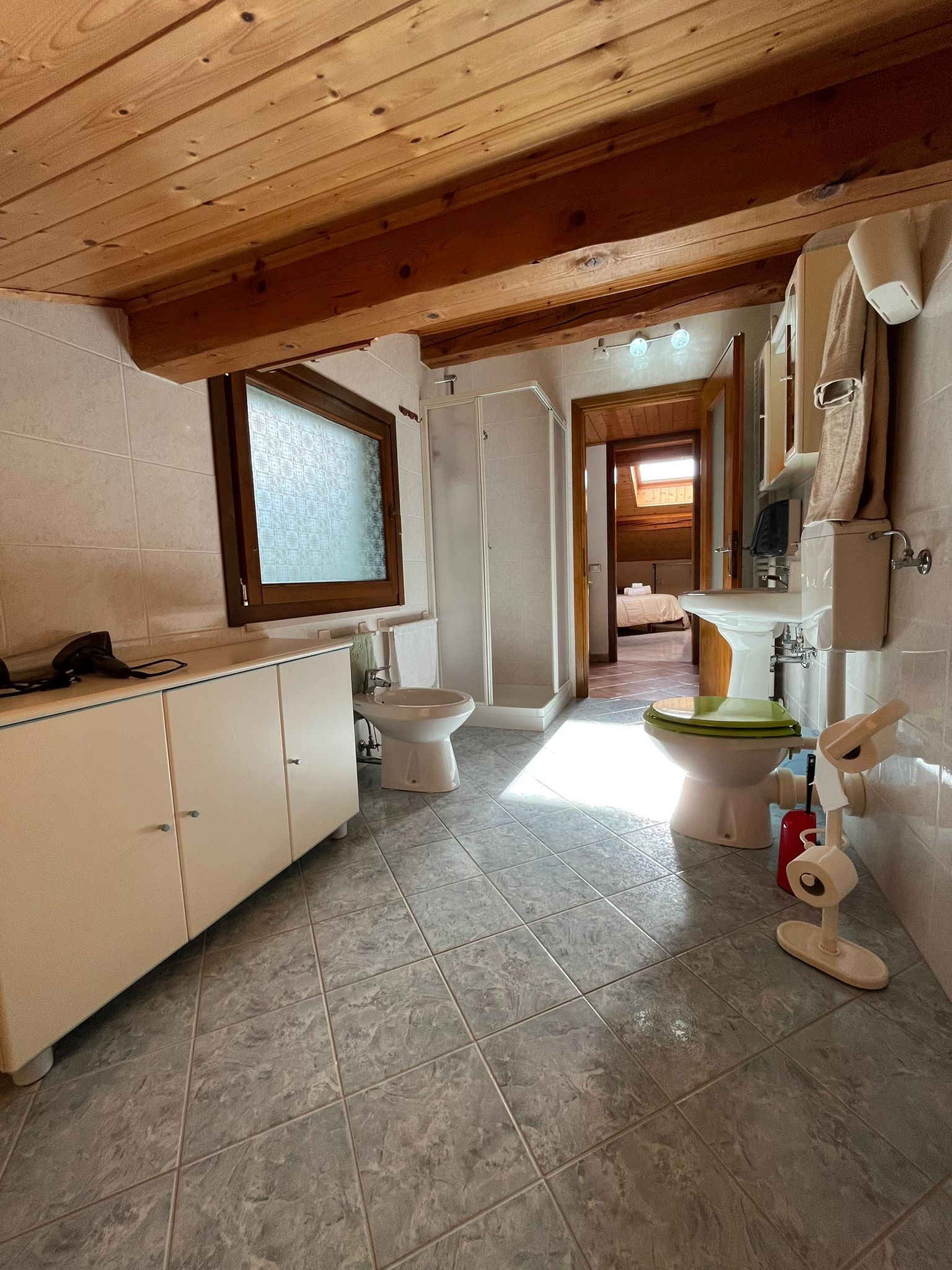 Une salle de bain avec un plafond en bois, des toilettes, un lavabo et un espace douche.