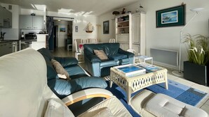 A living room with a sofa, armchairs, a coffee table, and a dining area with chairs and a table.